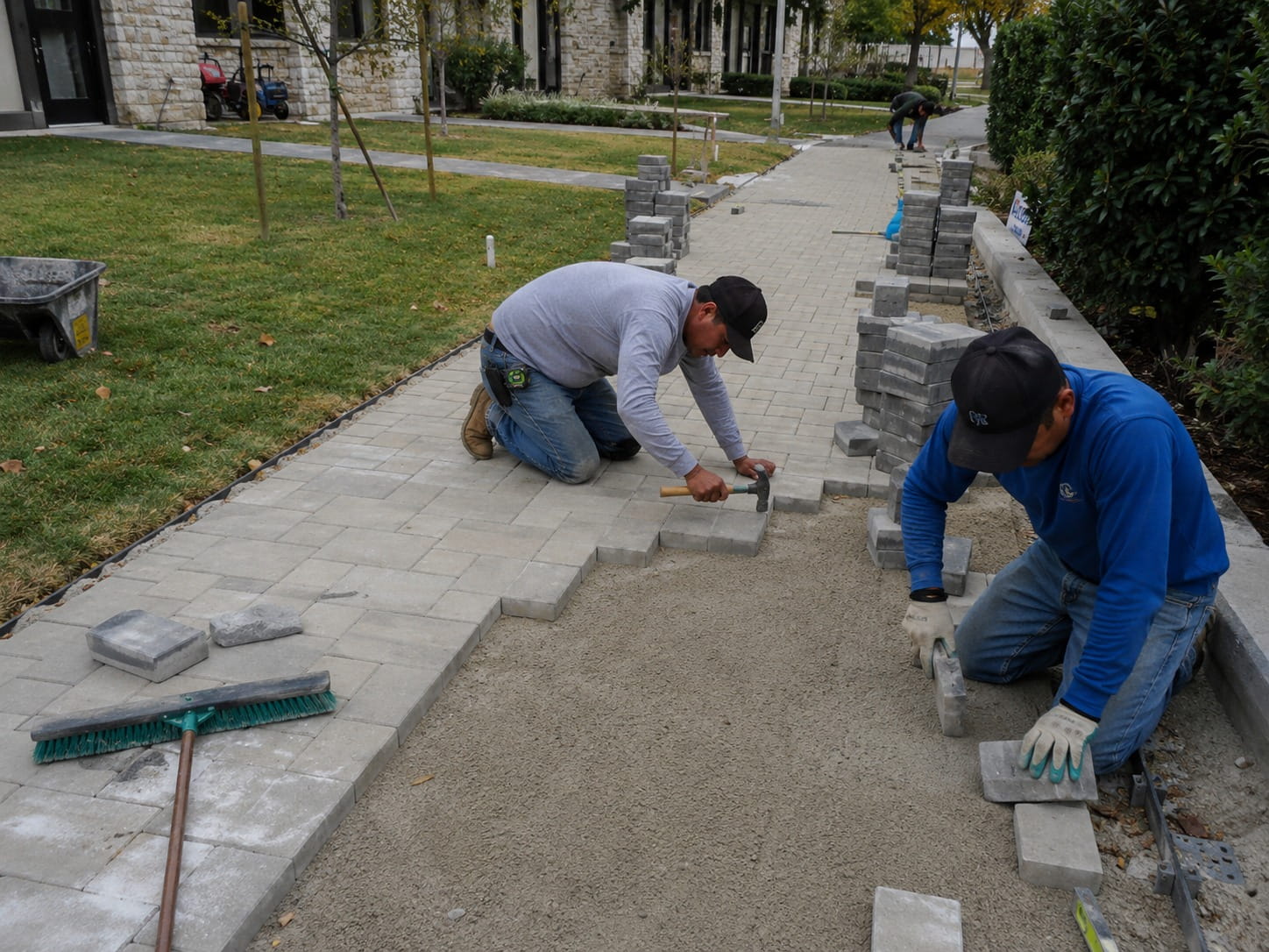 Tradesmen laying stone paving for an outdoor walkway at a Perth property